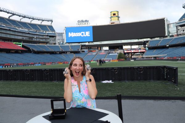 Woman standing on field at Gillette Stadium wearing super bowl rings