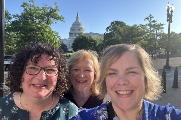 Three women take a selfie in front of the capital
