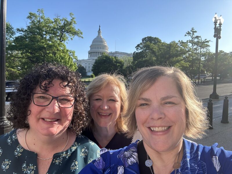Three women take a selfie in front of the capital
