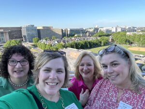 Four women smile with Washington DC in the background