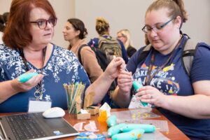 Two educators look down at a tool in the MassCUE Creativity Cafe