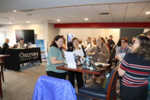 A group of educators gathers around a table top demonstration in the Educator Showcase